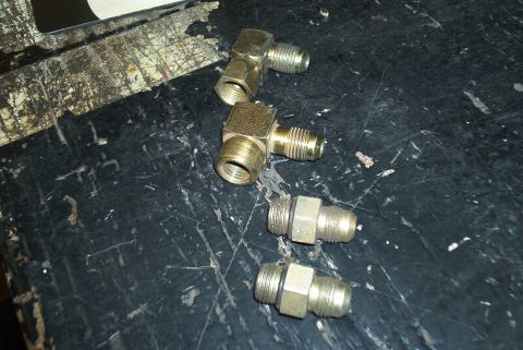 1983 Ford Bronco - Various brass fittings are arranged on a worn, dark workbench.