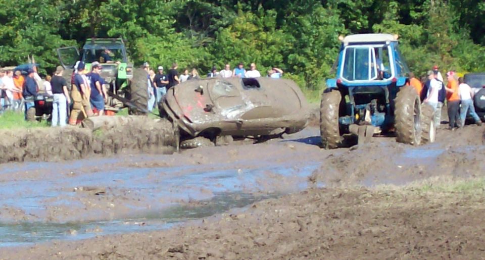 Tractors pulling a mud-covered vehicle out of a bog