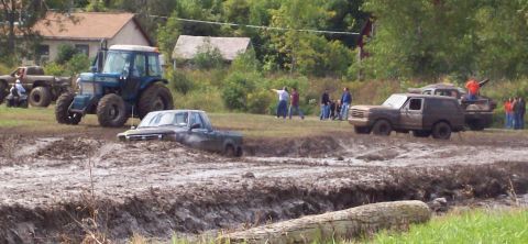 1979 Ford Bronco - Several vehicles are participating in a mud bogging event, with one truck deeply stuck in the mire.