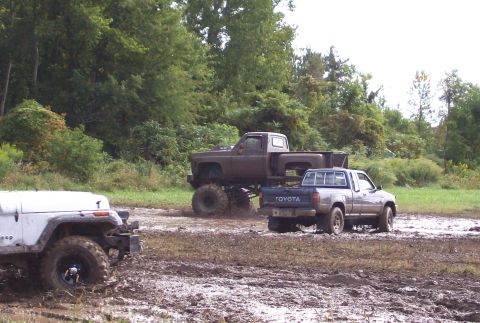 1979 Ford Bronco - Multiple off-road vehicles navigate a muddy terrain during an outdoor event.