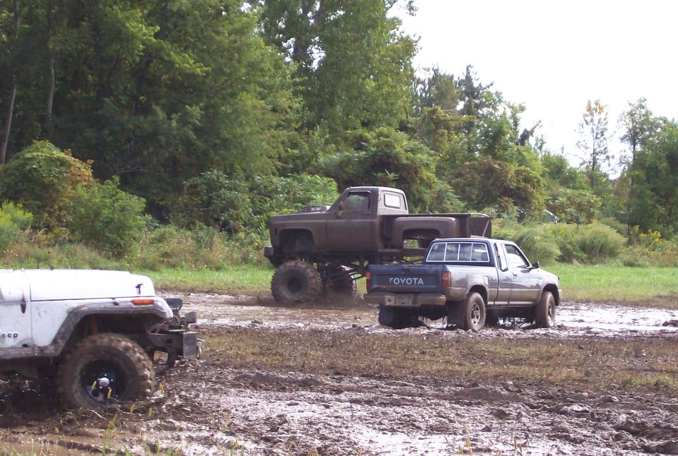 Muddy Toyota pickup truck and lifted pickup truck in a field