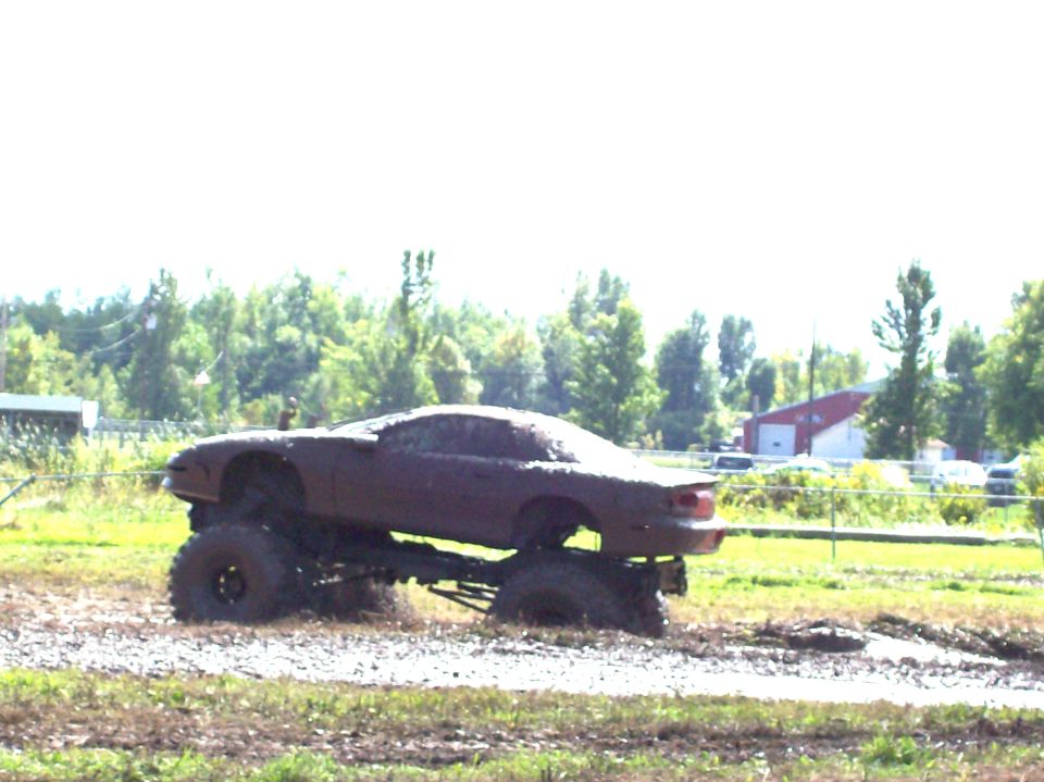 Mud-covered monster truck with large tires in a muddy field