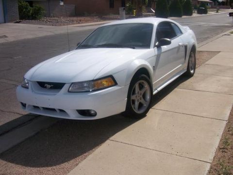 1978 Ford Mustang II - This white Ford Mustang is parked on a concrete sidewalk in a residential area.