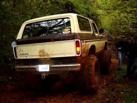 1992 Ford Mustang - This lifted 1978-1979 Ford Bronco is shown off-road in a muddy environment, with two individuals walking in the background.