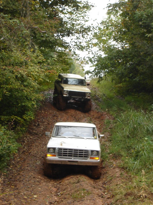 White 1979 Ford F-150 pickup truck driving through mud, front view