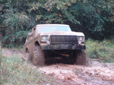 1992 Ford Mustang - A tan pickup truck navigates a muddy trail, kicking up dirt as it goes.