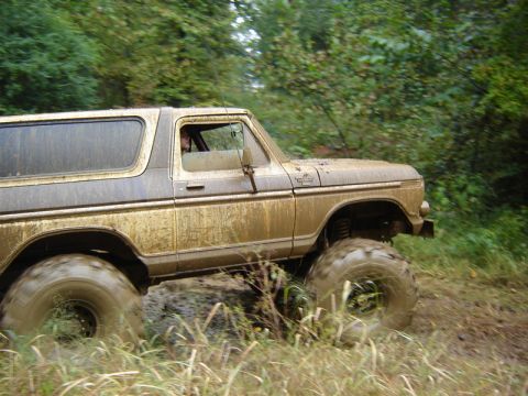 1992 Ford Mustang - A heavily muddied 1978 Ford Bronco navigates a challenging off-road terrain.