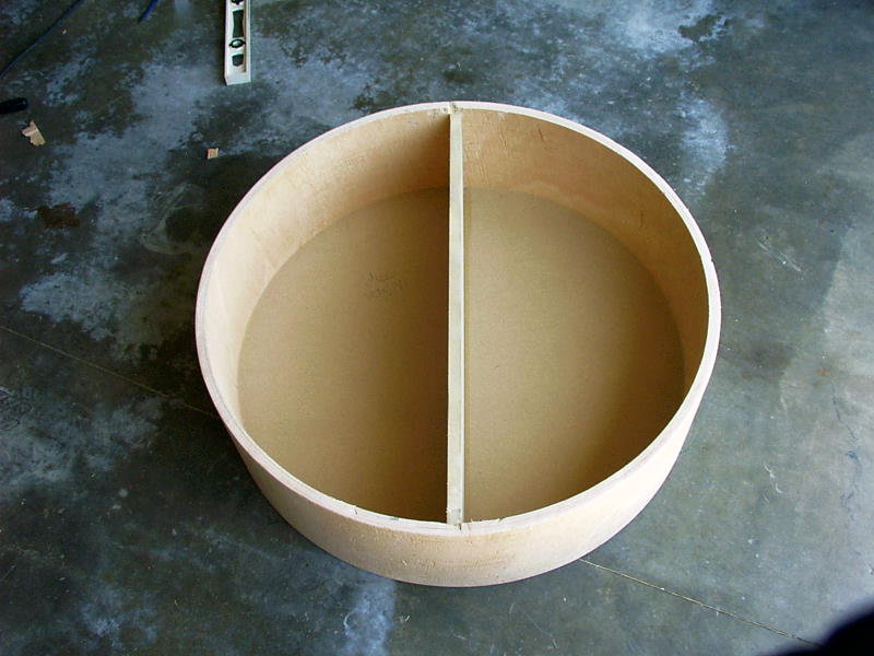 Round wooden enclosure with center divider on concrete floor