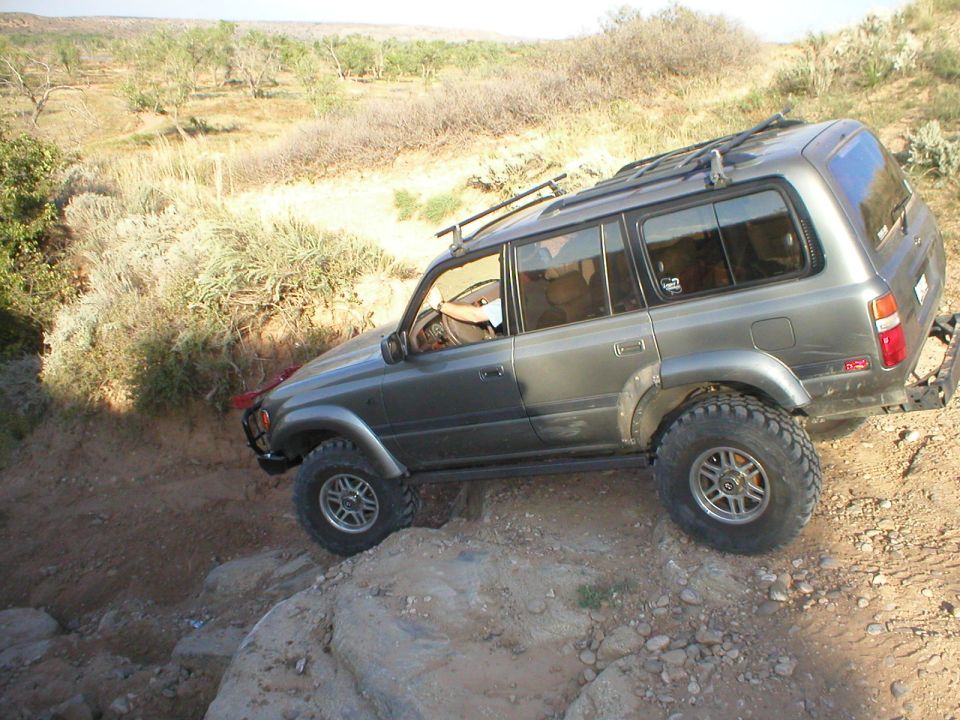 Gray Toyota Land Cruiser with roof rack navigating a rocky trail