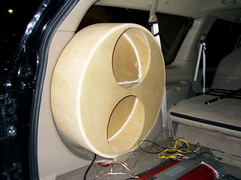2000 Ford Excursion - A custom-built speaker box is installed in the rear of a vehicle, with wiring visible on the floor and seats in the background.