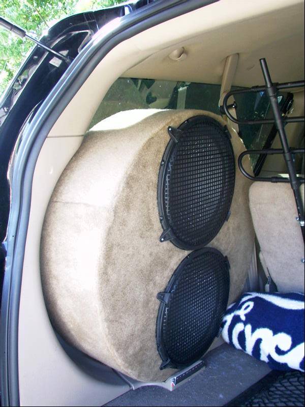 Custom carpeted dual subwoofer enclosure in tan SUV cargo area