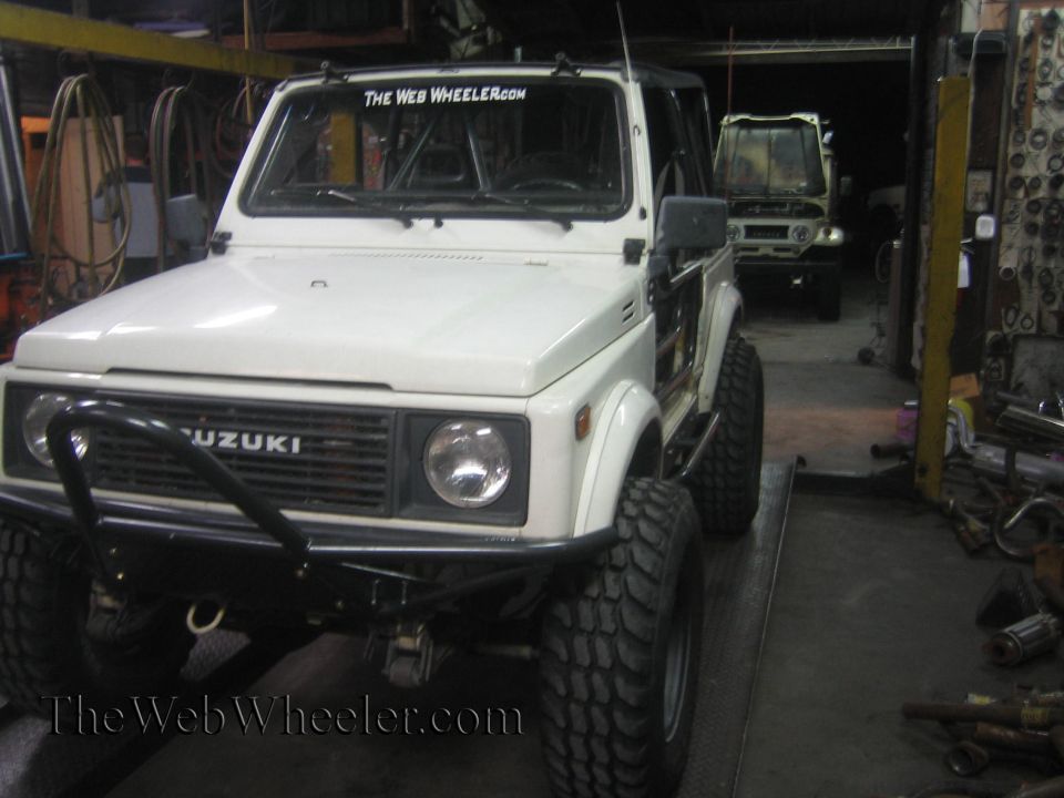 White 1987 Suzuki Samurai with off-road tires and custom bumper, another Samurai in background