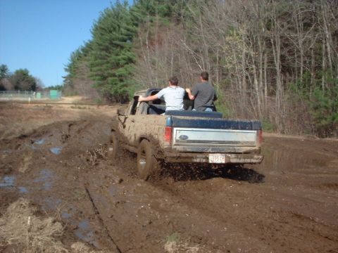 1978 Ford Bronco - A 1978 Ford F-Series pickup truck navigates a muddy track with two occupants in the cab.