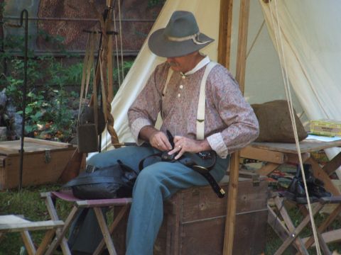 1966 Ford Ranchero - A man dressed in 19th-century clothing sits outdoors near a tent, appearing to be preparing equipment.