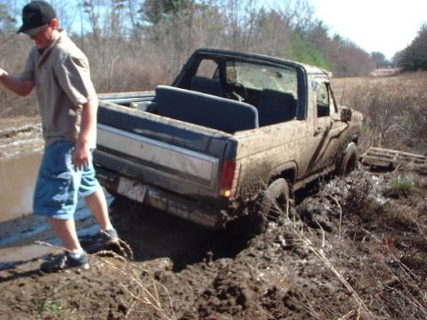 1978 Ford Bronco - A mud-covered pickup truck is stuck in a muddy field, with a person standing nearby.