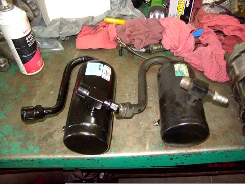 1988 Ford C-350 (Centurion Conversions) - Two black air conditioning receiver driers are shown on a workbench next to a can of starter fluid.