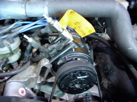 1988 Ford C-350 (Centurion Conversions) - Close-up view of engine components, including an AC compressor and associated plumbing and wiring.
