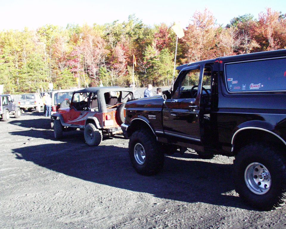 Black Ford Bronco with door open, parked on gravel lot