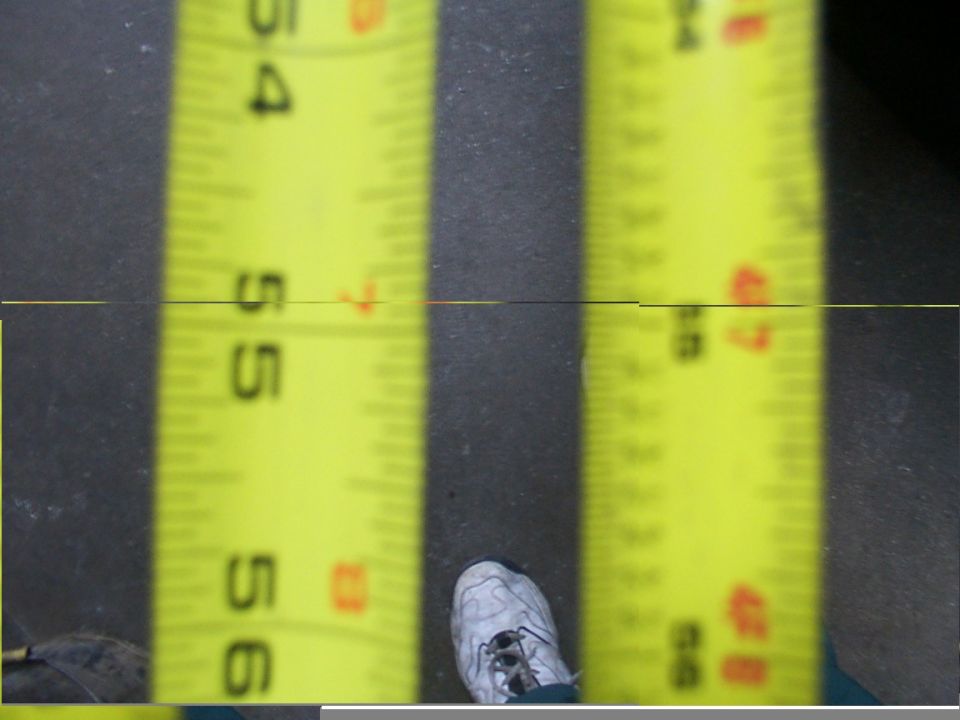Yellow tape measure blade reading 54 to 56 inches on a concrete floor beside a sneaker