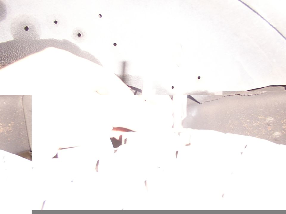 Overexposed close-up of drilled holes along a metal body lip with a rusty riveted flange
