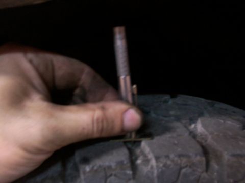 1988 Ford C-350 (Centurion Conversions) - Measuring tire tread depth with a gauge.