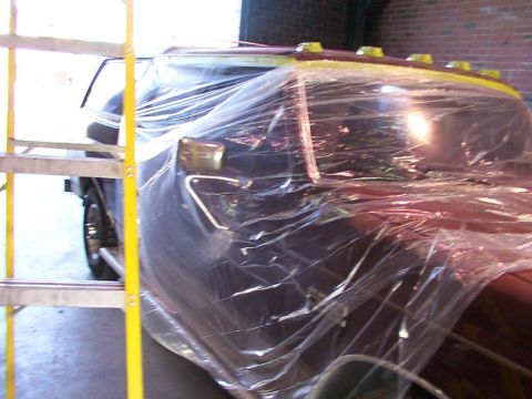 1988 Ford C-350 (Centurion Conversions) - A truck is covered in plastic sheeting, likely for painting, with a ladder positioned next to it.