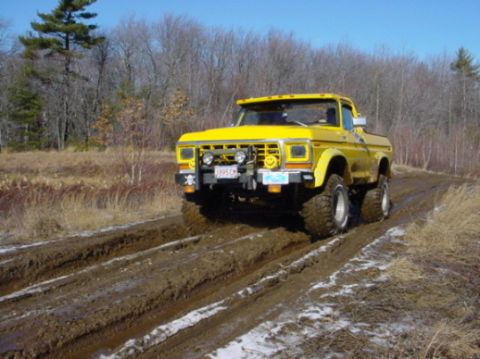 1978 Ford Bronco - A yellow 1978 Ford Bronco navigates a muddy track with large tires.