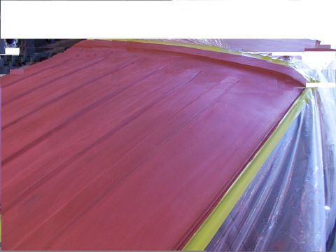 1988 Ford C-350 (Centurion Conversions) - A close-up view of a red painted surface, partially covered with yellow masking tape and plastic sheeting.
