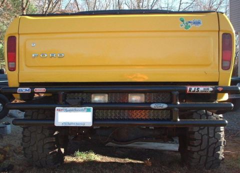 1978 Ford Bronco - Rear view of a yellow Ford truck, likely a 1979 model, a custom bumper and various stickers.