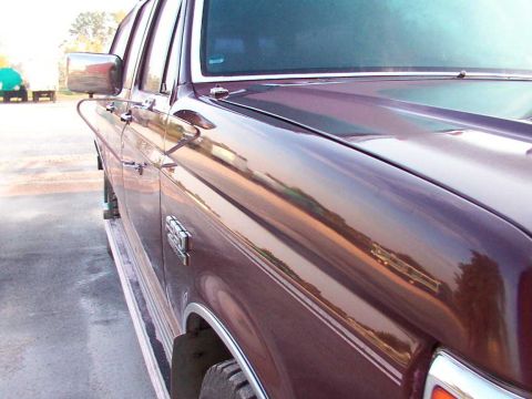 1988 Ford C-350 (Centurion Conversions) - A maroon Ford F-Series truck is shown from the side, with other vehicles reflected in its polished surface.