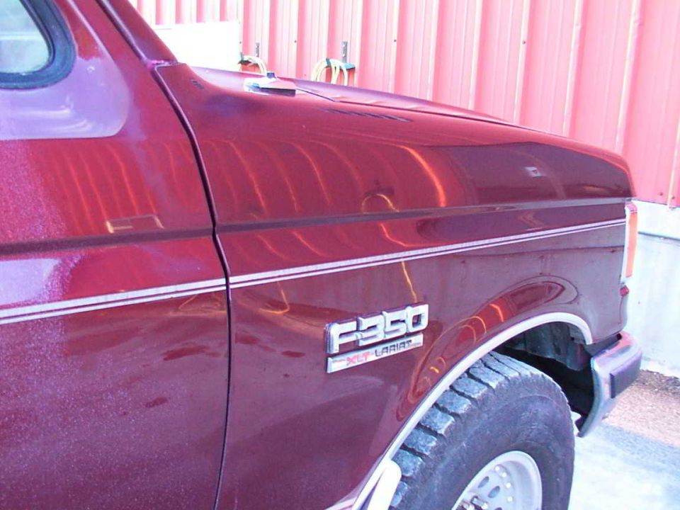 Red Ford F-350 XLT Lariat fender and hood detail. The vehicle has a chrome trim line