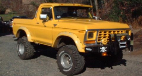 1978 Ford Bronco - A yellow 1978 Ford Bronco with a custom front bumper and off-road tires is parked outdoors.