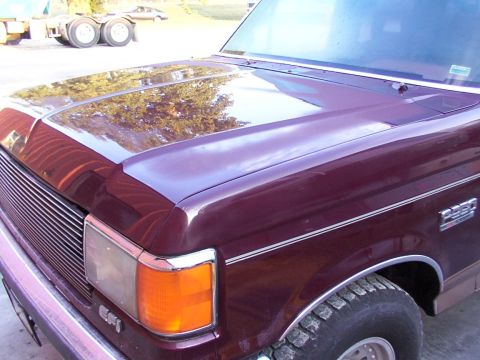 1988 Ford C-350 (Centurion Conversions) - Maroon Ford F-350 truck front corner shows chrome grille and orange turn signal light. A trailer is visible in the background.