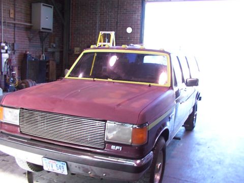 1988 Ford C-350 (Centurion Conversions) - Maroon Ford F-Series truck with yellow tape around windows, facing front-left in a garage.