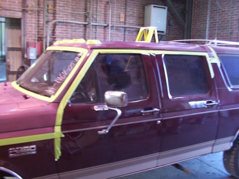 1988 Ford C-350 (Centurion Conversions) - Maroon van with yellow masking tape on windows and trim, with "116Y 050" written on the windshield.