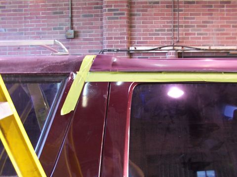 1988 Ford C-350 (Centurion Conversions) - Masking tape is applied to the roofline and window trim of a maroon vehicle, likely for a paint job.