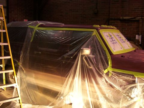 1988 Ford C-350 (Centurion Conversions) - A vehicle is covered in plastic sheeting and taped off, possibly for painting or detailing. Text on the window is partially visible.