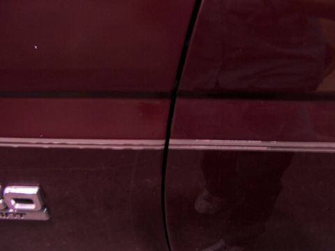 1988 Ford C-350 (Centurion Conversions) - Close-up of the side of a maroon 1988 Ford C-350 Centurion Conversions, showing the door seam and chrome trim.