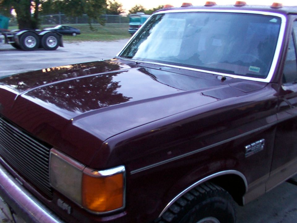 1988 Ford C-350 (Centurion Conversions) maroon front fender, hood, and grille. Other vehicles visible in background