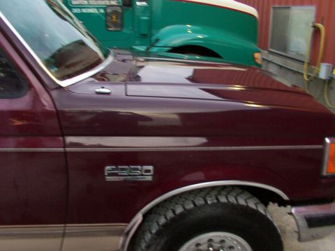 1988 Ford C-350 (Centurion Conversions) - A maroon Ford F-250 pickup truck is parked next to a green semi-truck.