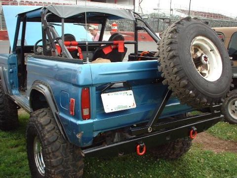 1978 Ford Bronco - Rear view of a blue 1978 Ford Bronco, a spare tire mounted externally and an open hood.