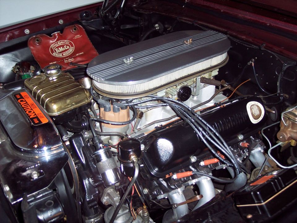 Engine bay of a 1963 Ford Galaxie with 406 V8, finned oval air cleaner, and red FoMoCo fender cover