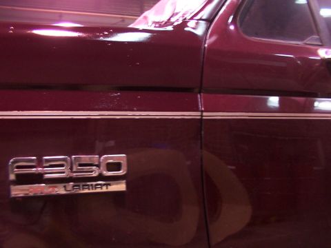 1988 Ford C-350 (Centurion Conversions) - Close-up of a maroon Ford F-350 Lariat's side panel, showing chrome trim and badging.
