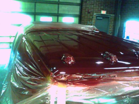 1988 Ford C-350 (Centurion Conversions) - The top of a vehicle is covered in plastic wrap, revealing red paint and lights.