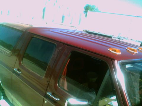 1988 Ford C-350 (Centurion Conversions) - The top section of a red pickup truck, showing the roofline and side windows, with amber marker lights.