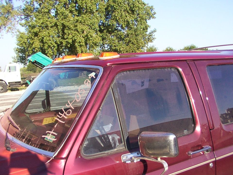 Side view of a red van with amber roof lights. Text is written on the windshield
