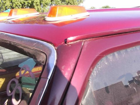 1988 Ford C-350 (Centurion Conversions) - Close-up of a red vehicle's roofline, showing amber lights and chrome trim.
