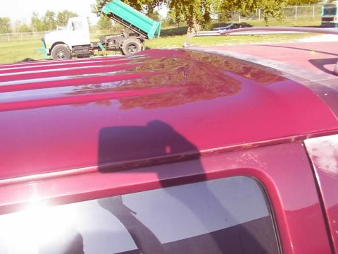 1988 Ford C-350 (Centurion Conversions) - A dump truck is visible in the background behind the roof of a red vehicle.
