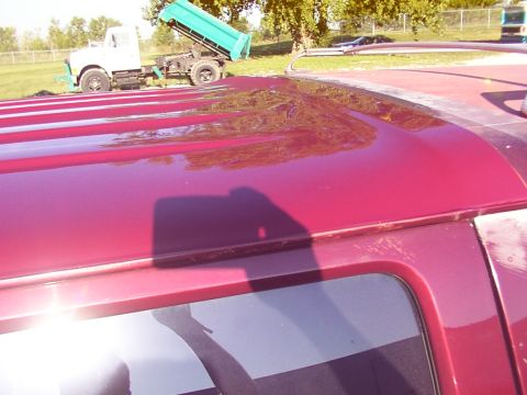 1988 Ford C-350 (Centurion Conversions) - The red van's roof shows damage, with a dump truck visible in the background.