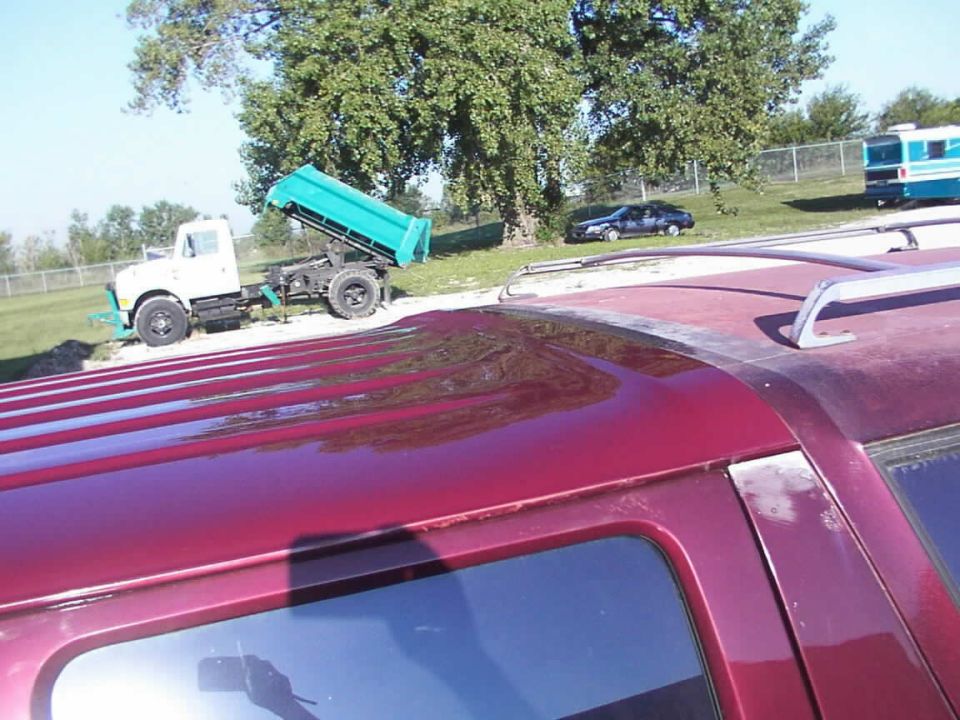 Red SUV roof rack, side view. Dump truck and car in background